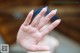 A woman's hand with a blue manicure on it.