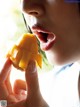 A woman eating a mango with her mouth open.