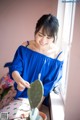 A woman in a blue off the shoulder top holding a cactus.