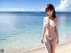 A woman in a white bikini standing on a beach.