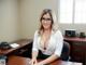 A woman in glasses sitting at a desk in an office.