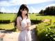 A woman in a white dress standing in a field.