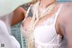 A woman in a white lingerie with pearls around her neck.