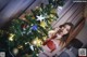 A woman in a red lingerie standing next to a Christmas tree.