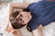 A woman laying on a bed with her hands on her face.