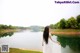 A woman in a white dress standing by a lake.