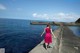 A woman in a pink dress walking along the edge of a pier.