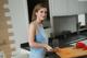 A woman standing in a kitchen preparing food on a cutting board.